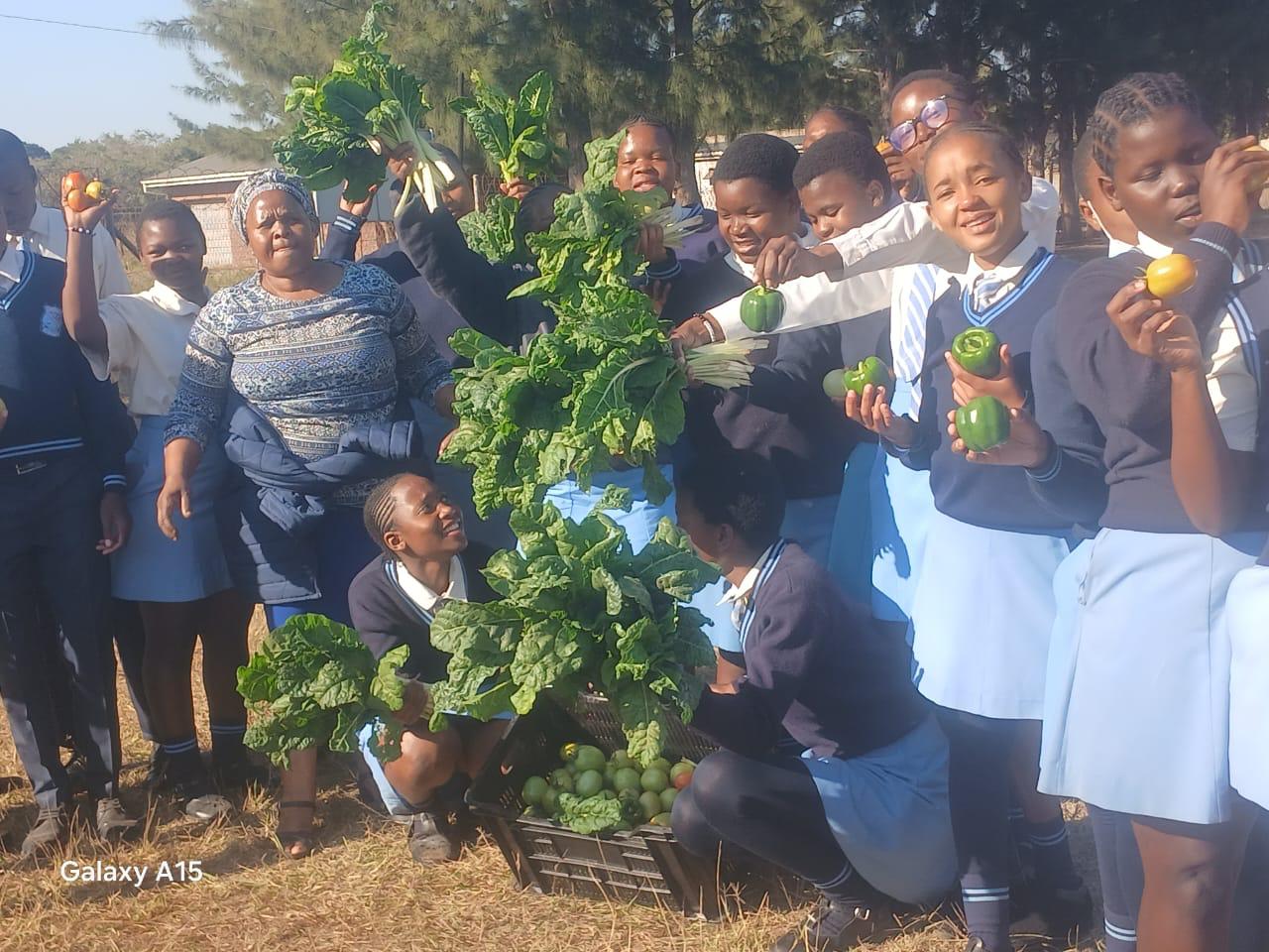 6 südafrikanische Schüler*innen präsentieren Körbe mit der ersten Ernte aus dem neuen Gewächshaus